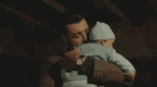 a man is holding a baby in his arms and kissing it on the cheek