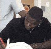 a man is sitting at a table writing on a piece of paper with a red pen .
