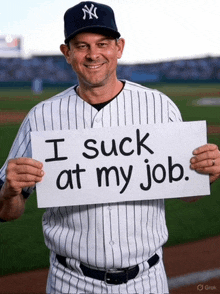 a man in a ny yankees uniform holds up a sign that says i suck at my job