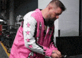 a man with a beard is wearing a pink and white jacket with stars on it .
