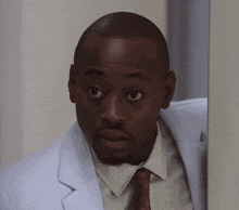 a man in a white coat and tie is looking at something