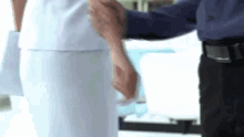 a man is holding the hand of a nurse in a hospital room .