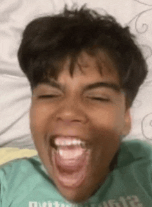 a young boy is making a funny face with his mouth open and his tongue sticking out .