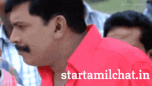 a man in a red shirt stands in front of a sign that says " starttamilchat.in "