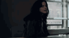 a woman sitting at a desk with a netflix logo on the bottom right