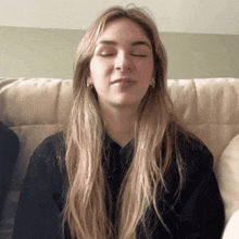 a woman with her eyes closed is wearing a black sweater