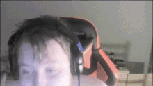 a man wearing headphones looks at the camera in front of an orange chair