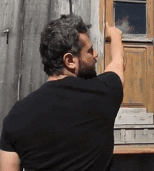 a man in a black shirt is standing in front of a window