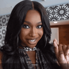 a woman wearing hoop earrings and a choker is smiling and giving the middle finger