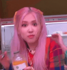 a woman with pink hair is holding a bottle of orange juice and a spoon .