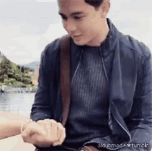 a man in a blue jacket is holding another man 's hand while looking at his watch .