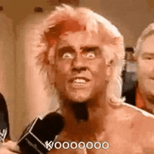 a man with a mullet is talking into a microphone .