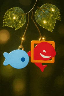 a blue fish and a red fish hanging from a tree branch