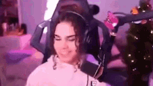 a woman is sitting in a gaming chair with headphones on .