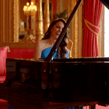 a woman in a blue dress is playing a steinway grand piano