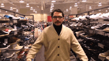 a man with a mustache and glasses is standing in a shoe store with a sign that says ' 876 ' on it