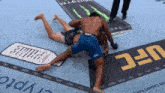 two men are wrestling on a ufc advertisement mat