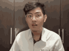 a man wearing glasses and a white shirt with ust on it
