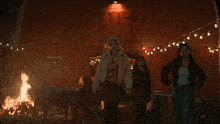 a group of women are standing in front of a fire