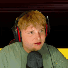 a young man wearing headphones and a green shirt talks into a microphone