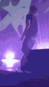 a man in a black shirt is standing on a stage in front of a purple background