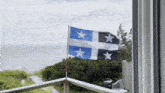 a blue and white flag with two white stars is flying on a balcony overlooking the ocean