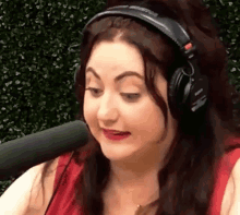 a woman wearing headphones is talking into a microphone and making a funny face .