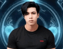 a young man in a black shirt is standing in front of a blue circle .