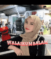 a woman in a hijab is standing next to elmo and the words " awalikumsalam "