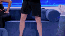 a man in black shorts is standing on a blue couch