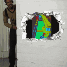 a man wearing headphones is looking through a hole in a wall at a video game