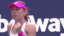 a woman wearing a pink visor is standing in front of a sign that says beway