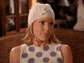 a woman wearing a polka dot top and a white hat