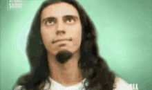a close up of a man with long hair and a beard looking up .