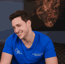 a man wearing a blue shirt that says dr. michal hawkins d.d. family medicine laughs
