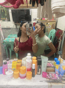 two girls are taking a selfie in front of a mirror with a phone that says ' i love you '
