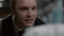 a close up of a man 's face in a suit and tie looking at something .
