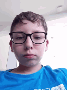 a young boy wearing glasses and a blue shirt is making a funny face