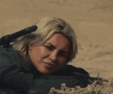 a woman laying down with a rifle in her hand