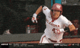 a baseball player wearing an oklahoma jersey runs towards home plate