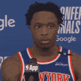 a man wearing a ny york jersey stands in front of a microphone