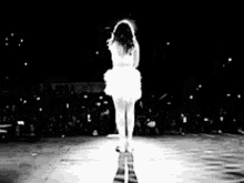 a black and white photo of a woman standing on a stage .