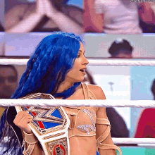 a woman with blue hair is holding a world heavyweight wrestling belt