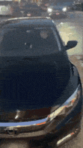 a man is driving a black honda car on a street