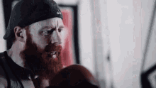 a man with a beard wearing boxing gloves and a black hat