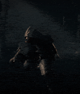 a man in a hooded cloak stands in the dark