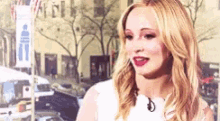a woman with blonde hair and red lipstick is standing in front of a microphone .