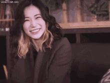 a woman in a suit is laughing with her mouth open in a room .