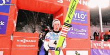 a person holding a pair of skis in front of a sign that says ylo