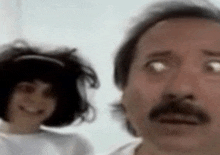 a man with a mustache is standing next to a girl with short hair .